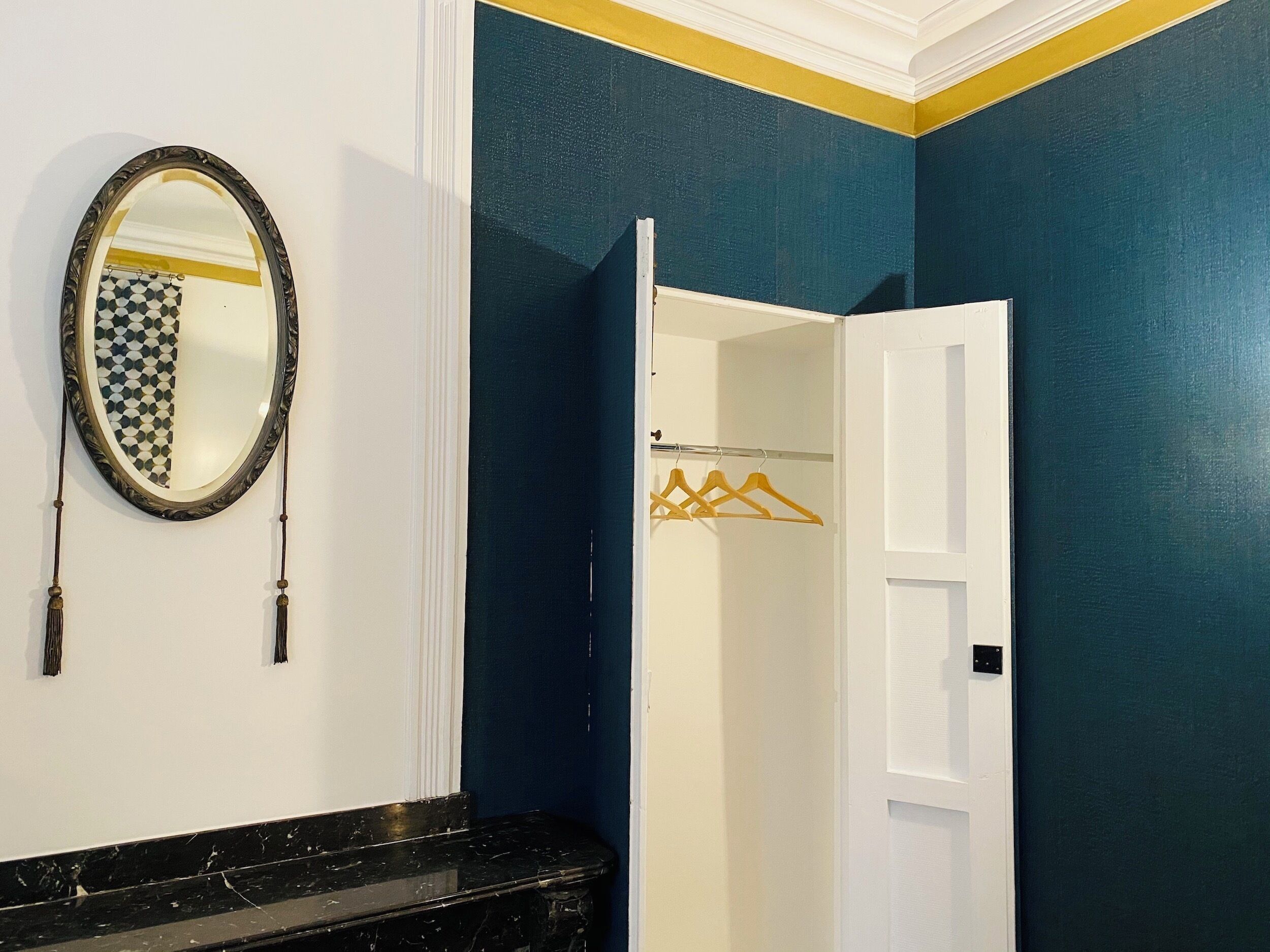 Un baño con pared azul oscuro, puerta blanca y encimera de mármol negro.
