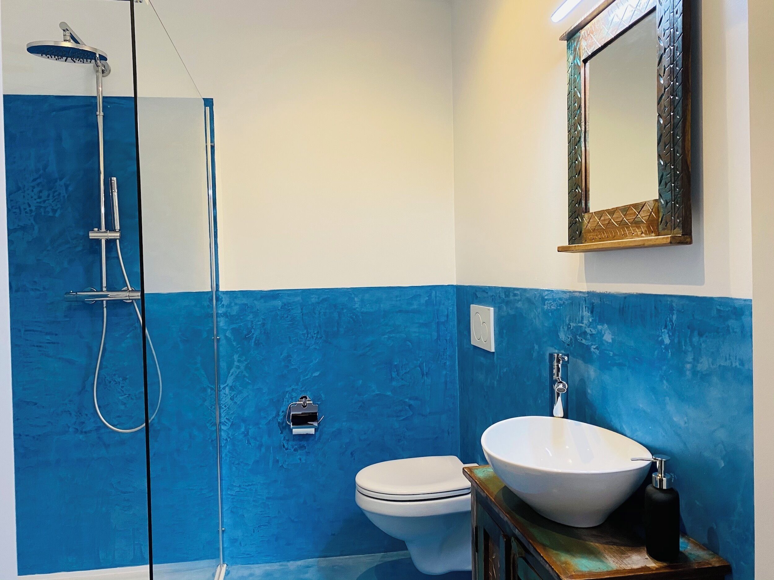 Une salle de bain avec une douche à parois de verre, des toilettes et un lavabo avec un miroir au-dessus.