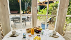 A dining table set for two with a view of the garden through large windows. - Aux Berges du Libre (Félines-Termenès)
