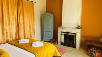 Un dormitorio con cama, armario, chimenea y una mesita.