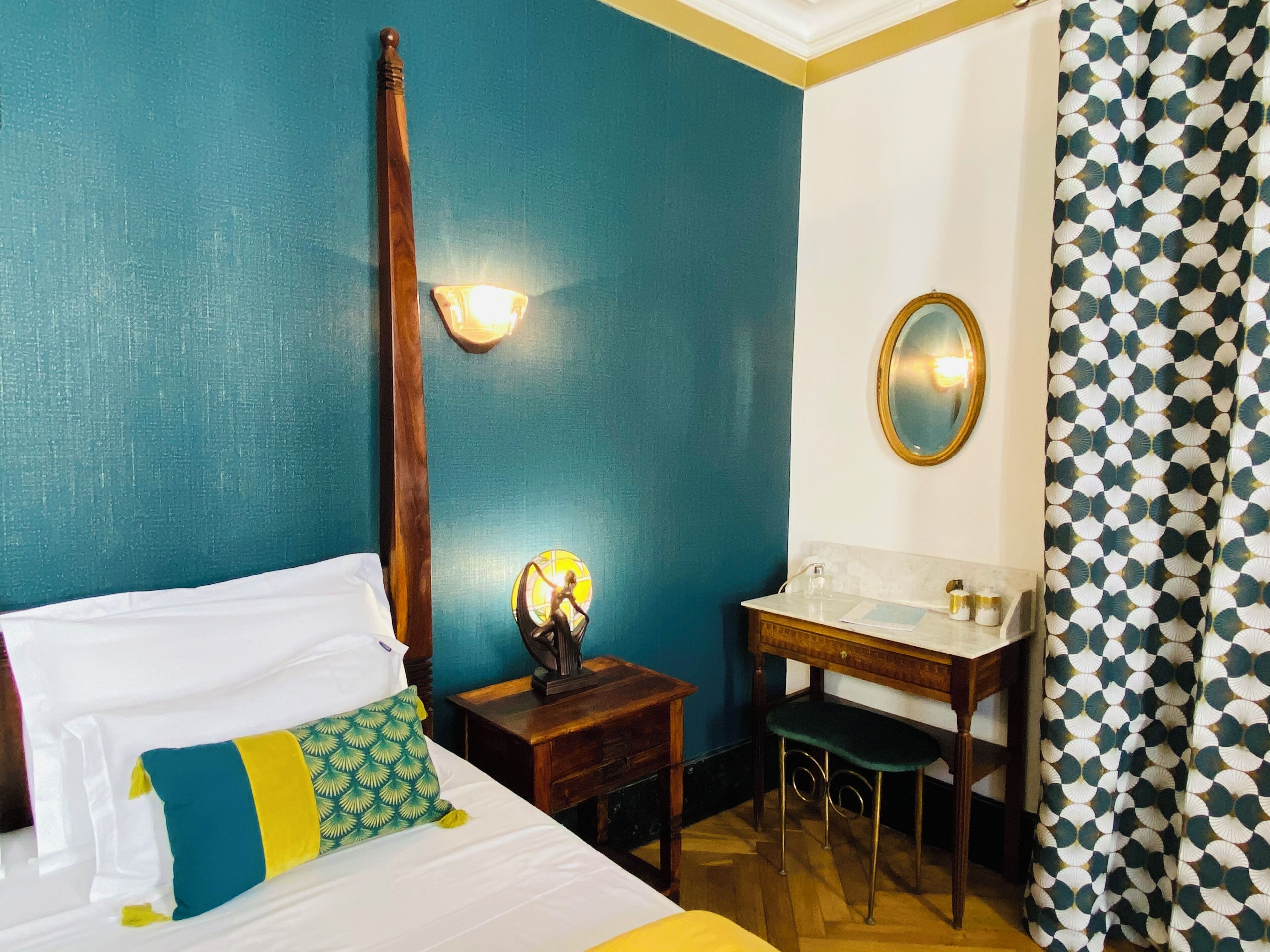A hotel room with a bed, a desk, a mirror, and a bathroom.