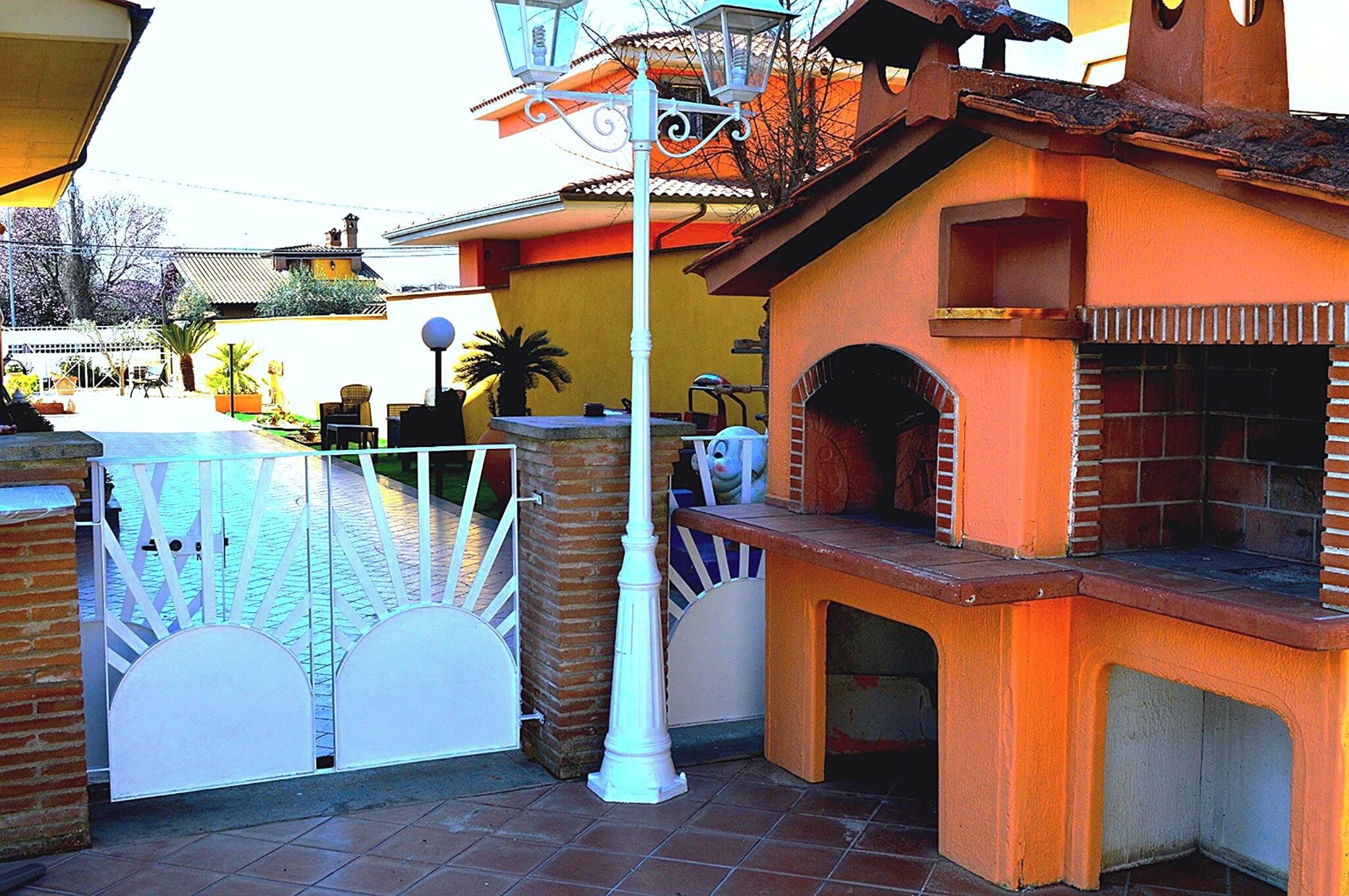 A courtyard with a brick barbecue area, a white gate, and a lamp post.