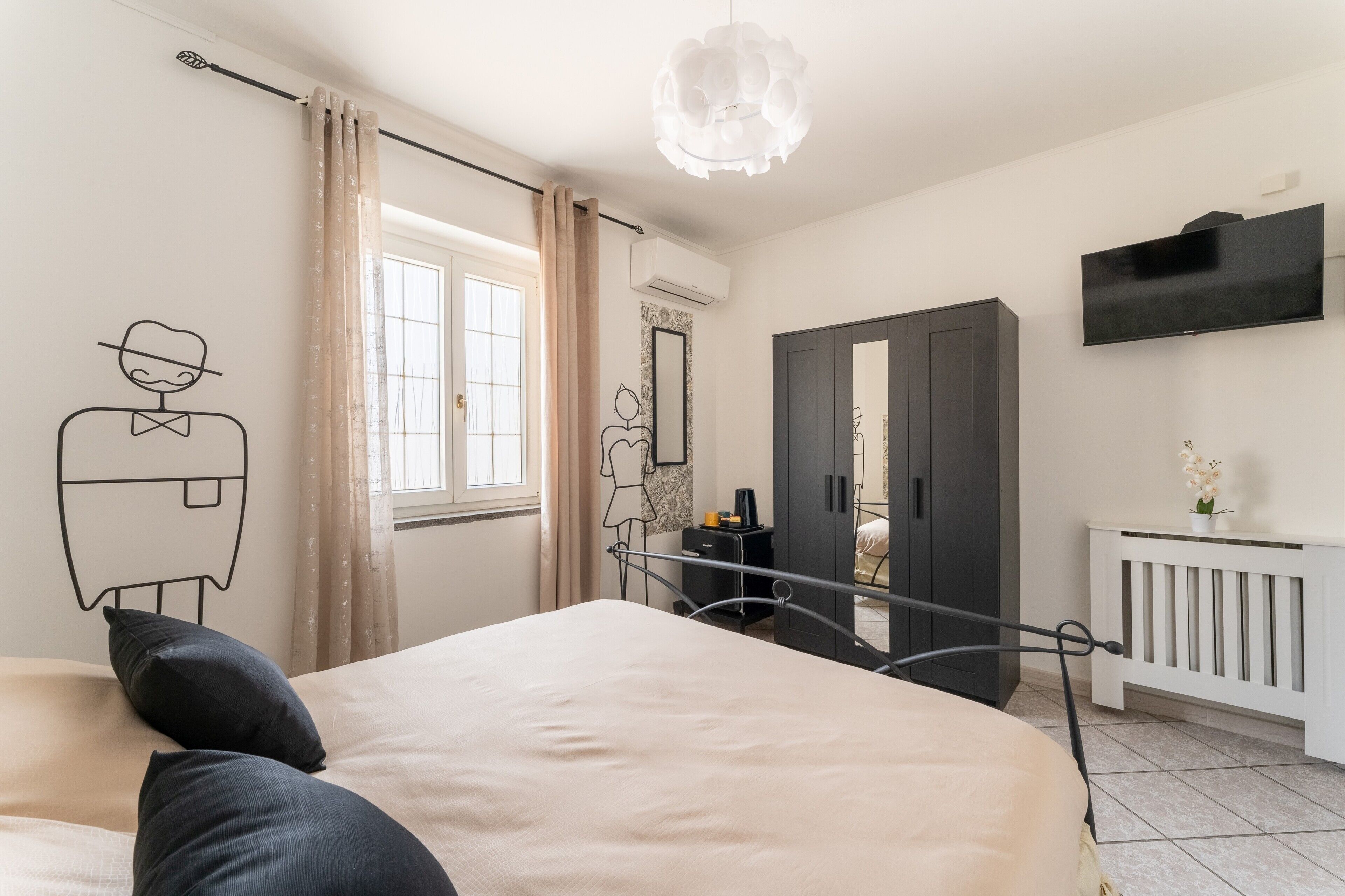 A bedroom with a bed, a wardrobe, a television, and a window with curtains.