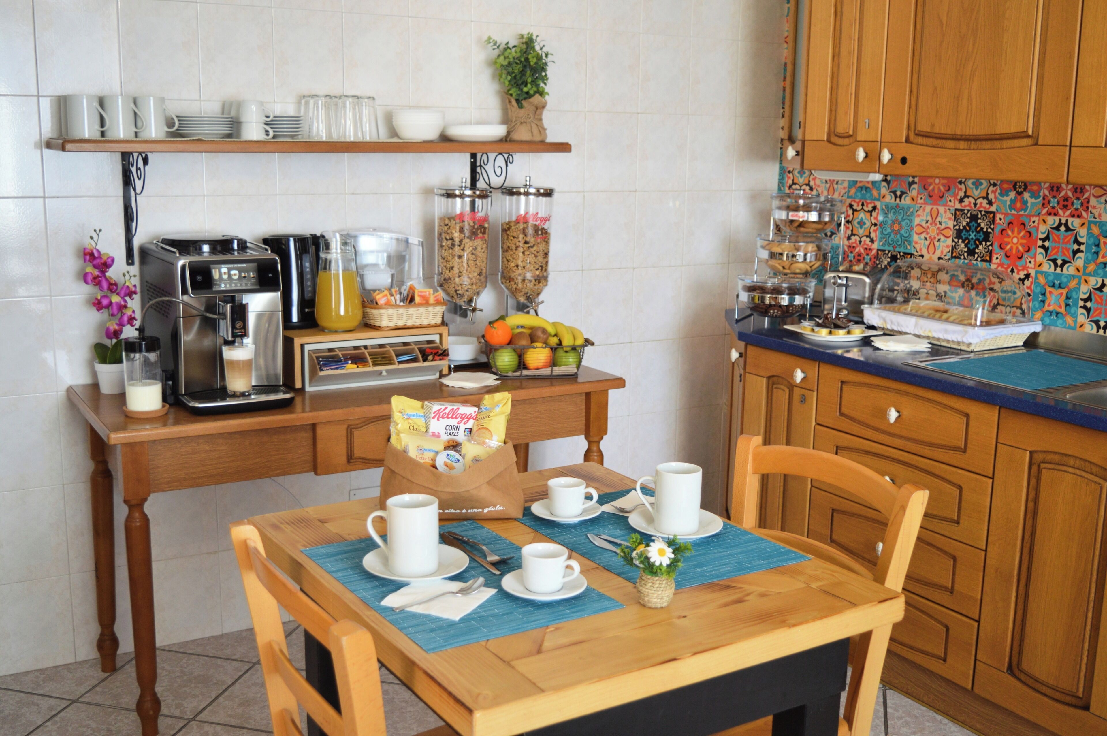 Un desayuno con cafetera, fruta y cereal sobre una mesa de madera.