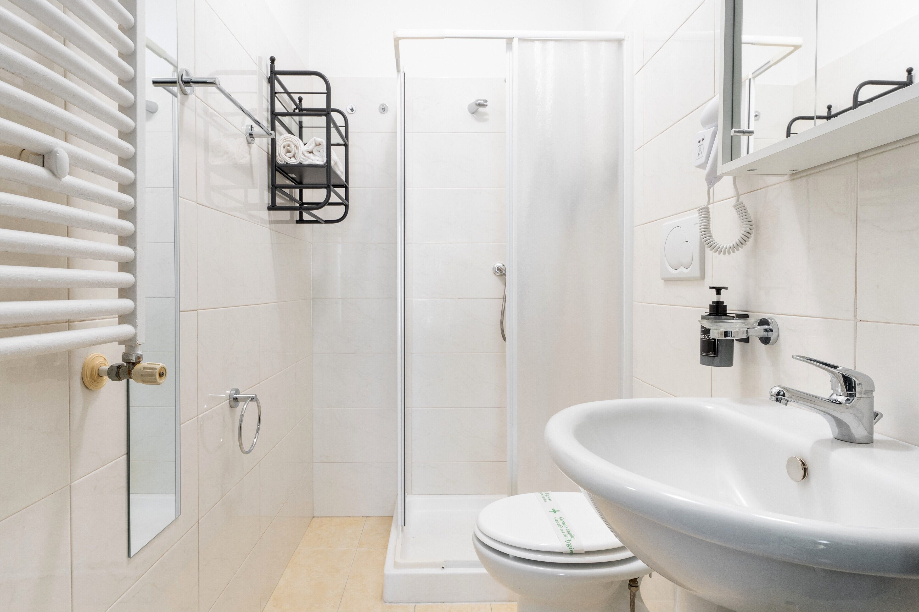 A modern bathroom with a white sink, a glass shower enclosure, and a toilet.