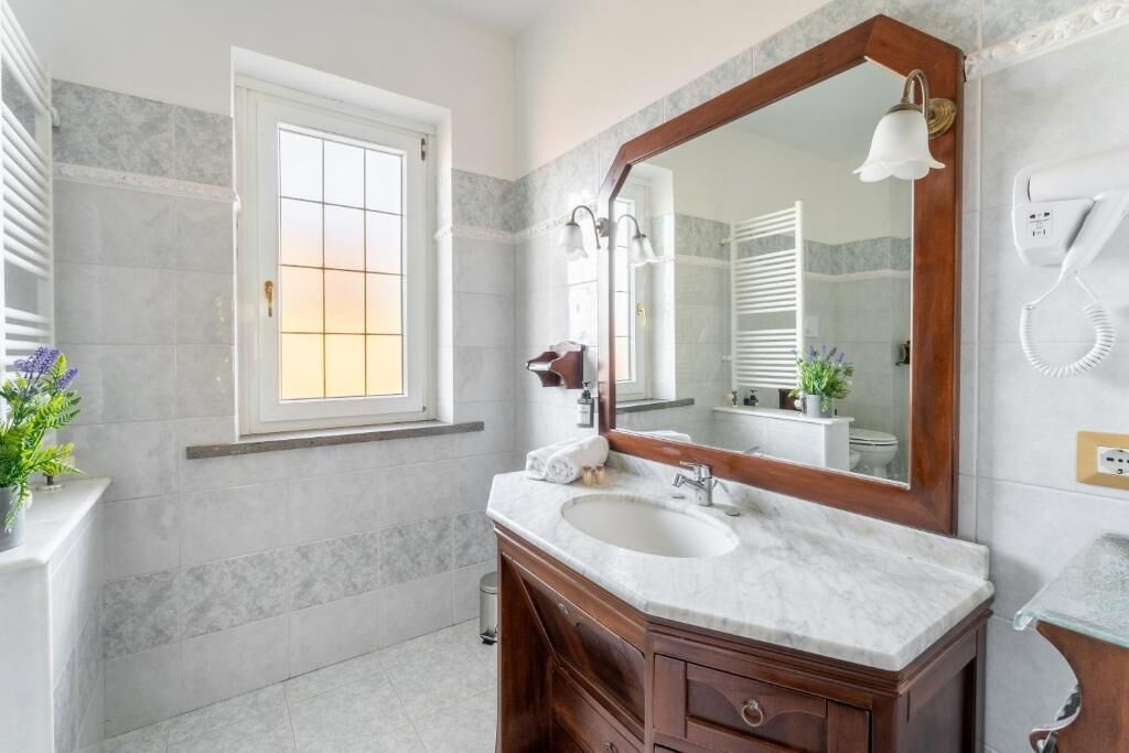 Un baño con un espejo grande, un lavamanos y una ventana.