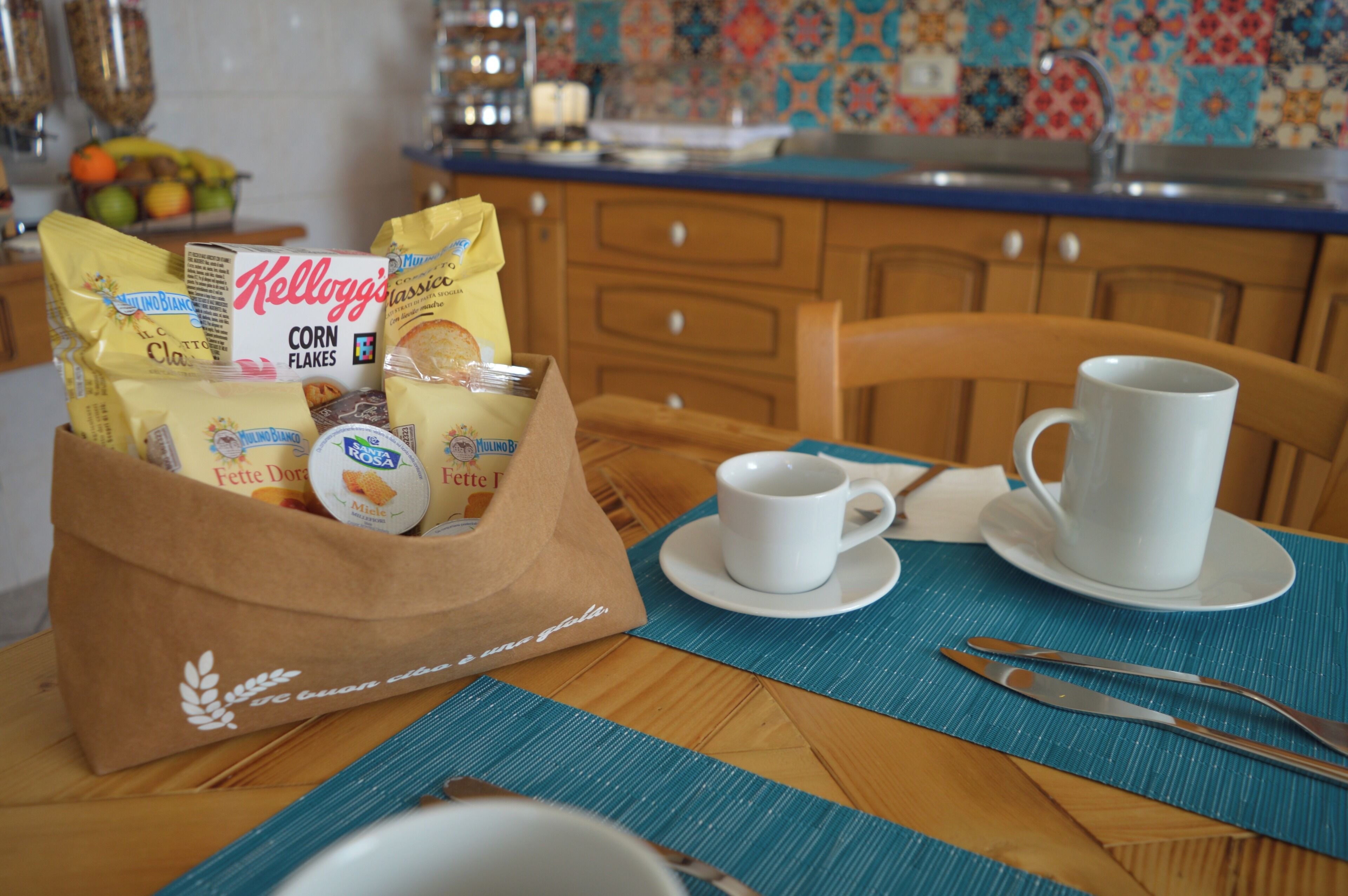 A breakfast setting with a bag of groceries, a mug, and a plate on a table.