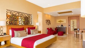 A hotel room with a large bed, a desk, and a chair. There is a ceiling fan and artwork on the walls.