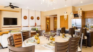 A modern dining area with a round table, chairs, and a chandelier.