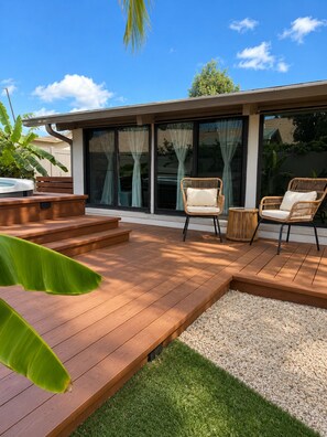 A modern outdoor deck with a hot tub, wicker chairs, and a small table.