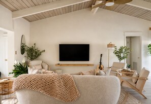 Una sala moderna con un televisor de pantalla plana grande, asientos cómodos y un ventilador de techo.