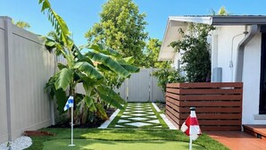 Un patio trasero bien cuidado con césped artificial, cerca de madera y un pequeño jardín.