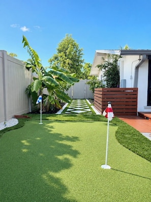 A well-maintained backyard with artificial grass, a wooden fence, and a small garden area.