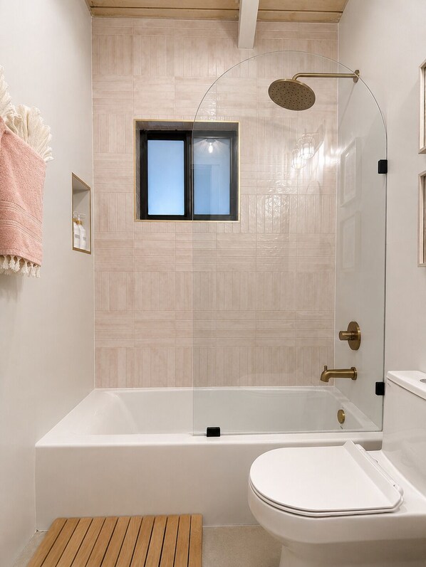 Un baño moderno con bañera, inodoro y zona de ducha.