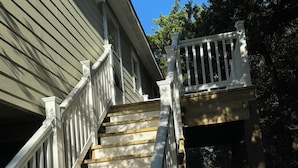 A wooden staircase with white railings leading to a deck.
