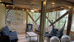 An outdoor patio with wooden furniture, a hammock, and string lights.