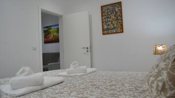 Una habitación de hotel con una cama, un cuadro en la pared y una puerta que da a otra habitación.