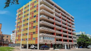 A multi-story residential building with balconies and a parking area in front. - Charming 1BR Retreat in Denver (Denver)