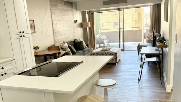 A modern kitchen with a central island, bar stools, and a dining area with a table and chairs. - Charming 1BR Retreat in Denver (Denver)