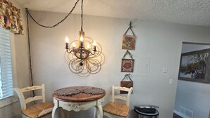 A dining area with a round table, two chairs, a chandelier, and vintage wall decorations. - Charming furnished 2-bedroom, 1 bath apartment with WiFi, AC in lovely Kalispell (Kalispell)