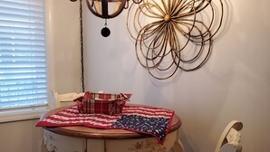 A dining area with a table set for two, a chandelier, and a wall art piece. - Charming furnished 2-bedroom, 1 bath apartment with WiFi, AC in lovely Kalispell (Kalispell)