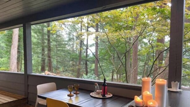 A modern dining area with a view of a forest through large windows.