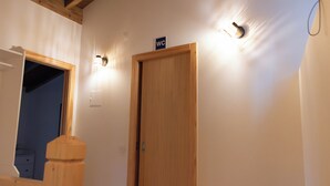 Una puerta de madera con un letrero encima, una lámpara en la pared y una barandilla de madera.