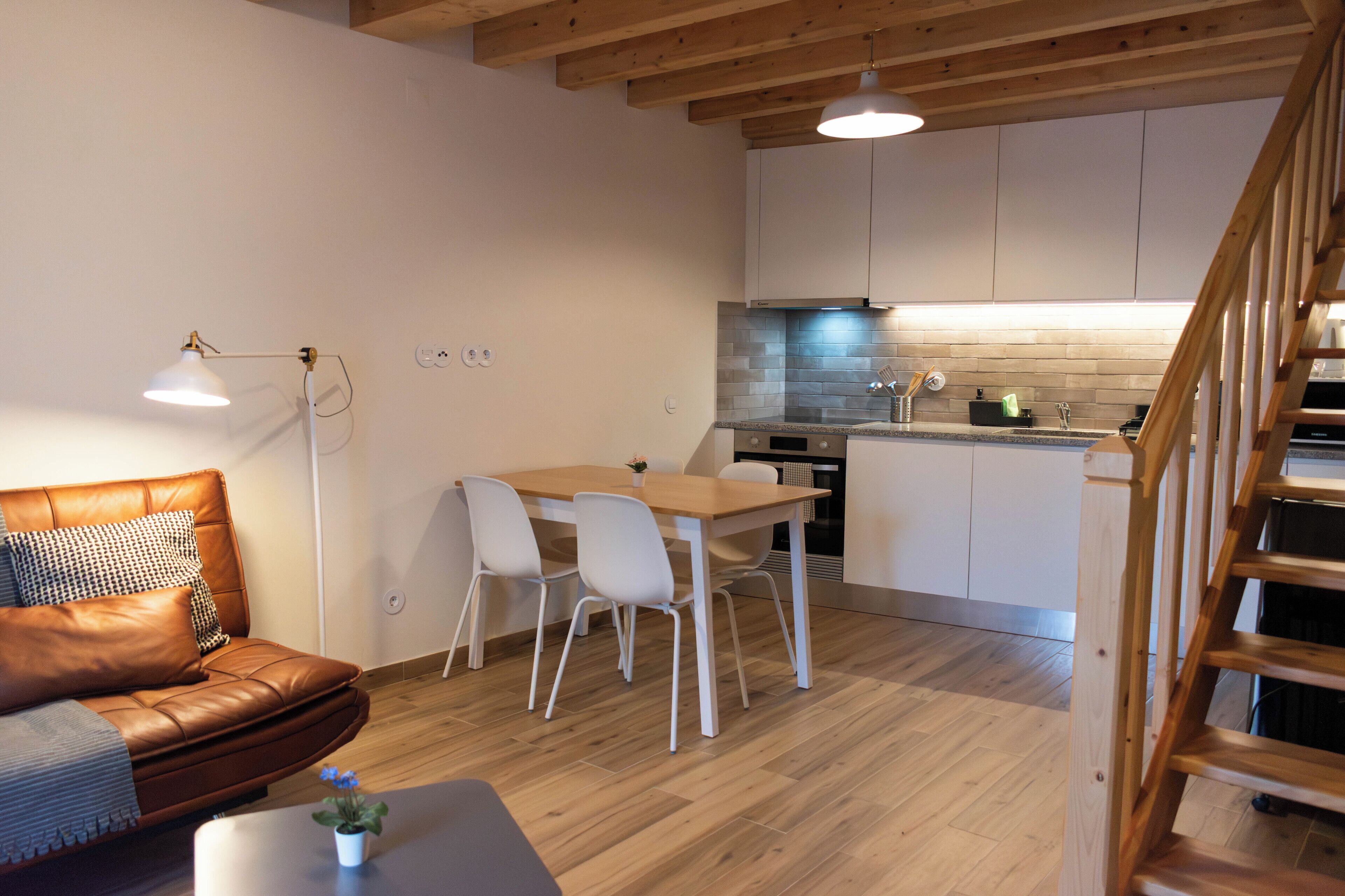 Une cuisine moderne avec des meubles blancs, une table à manger en bois et une cuisinière encastrée.