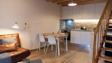 Une cuisine moderne avec des meubles blancs, une table à manger en bois et une cuisinière encastrée.