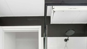 A modern bathroom with a shower, toilet, and a built-in washing machine.