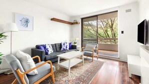 A modern living room with a sofa, armchairs, a coffee table, and a TV.