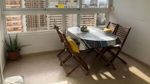 A dining area with a table and chairs, large windows with a city view, and a potted plant. - Gemelos 22, Benidorm-Alicante (Benidorm)