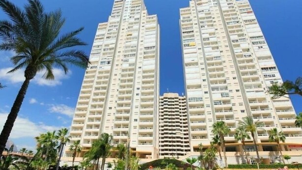 A high-rise hotel with multiple balconies, a swimming pool, and palm trees. - Gemelos 22, Benidorm-Alicante (Benidorm)