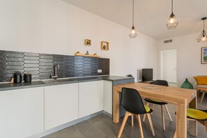 Eine moderne Küche mit weißen Schränken, einer schwarzen und grauen Spritzschutzwand und einem Holztisch mit Stühlen.