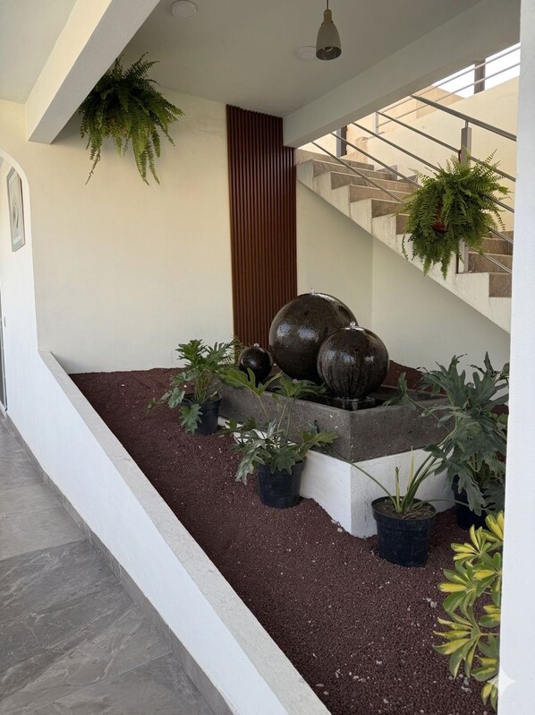 A modern indoor space with a staircase, potted plants, and a water feature. - Hotel Villa Veral (Teotihuacan)