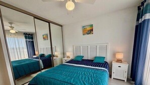 A bedroom with a large bed, a mirror, a ceiling fan, and a nightstand with a lamp. - QUIBERON - T2 - 50m2 - Port-Haliguen (QUIBERON)