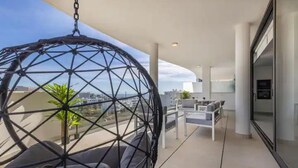 A modern balcony with a hanging chair, a sofa, and a dining area. - Bossa Nova | pool - terrace - fuengirola (Fuengirola)