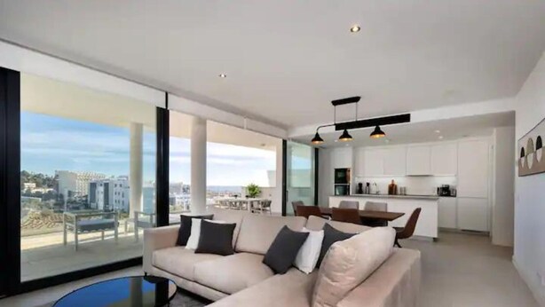 A modern living room with a sofa, a coffee table, and a view of the city. - Bossa Nova | pool - terrace - fuengirola (Fuengirola)
