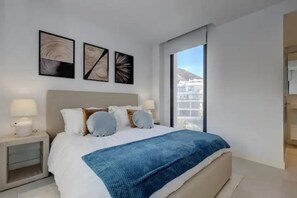 Ein modernes Schlafzimmer mit einem großen Bett, Nachttischen und Bildern an der Wand.