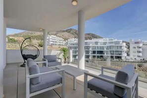 A balcony with modern furniture and a view of buildings in the distance. - ViVi Homes pool, Bossa nova apartment (Fuengirola)