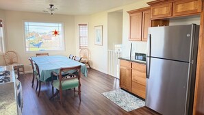 Une cuisine avec des meubles en bois, un réfrigérateur en acier inoxydable, une table à manger avec des chaises et une vue par la fenêtre.