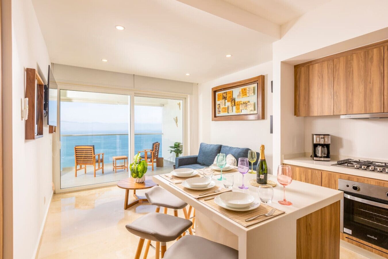 A modern kitchen with a dining area, a view of the sea, and wooden cabinets.