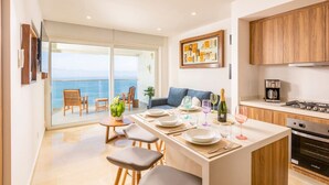 A modern kitchen with a dining area, a view of the sea, and wooden cabinets.
