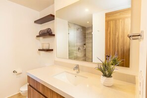 Un baño moderno con un espejo grande, un lavabo y una zona de ducha.