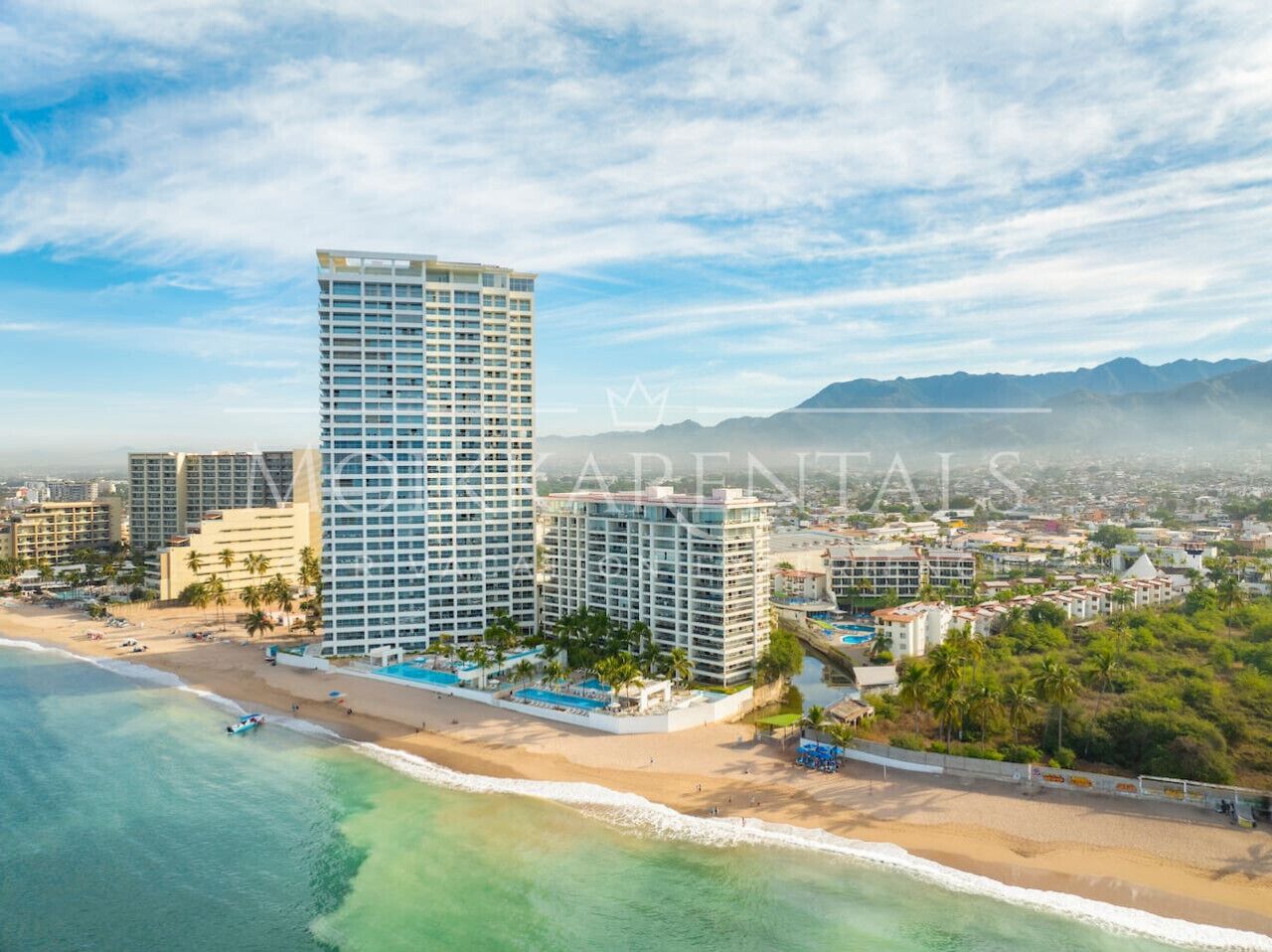 A coastal hotel with multiple high-rise buildings, a beachfront, and a pool area.