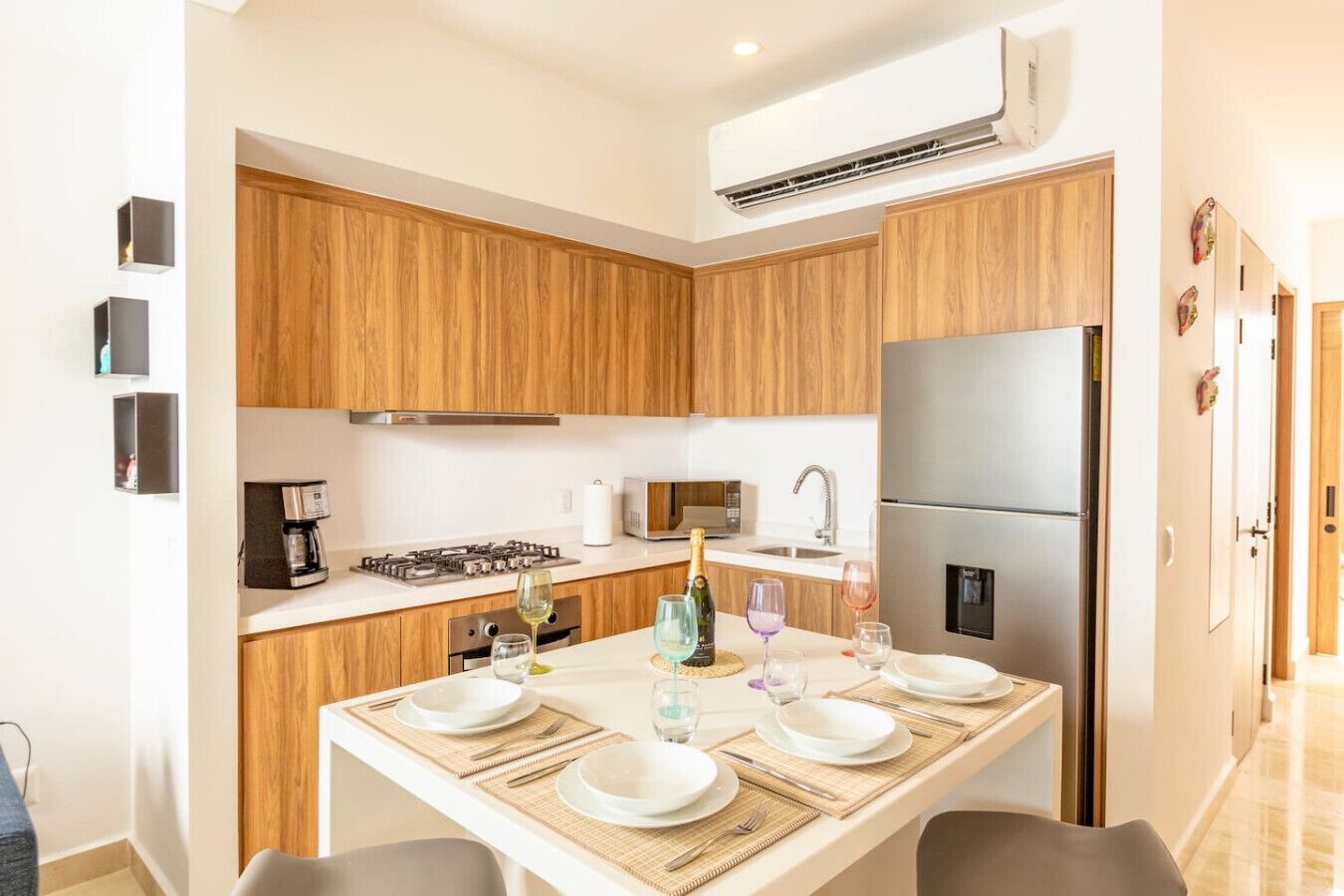 Eine moderne Küche mit Holzschränken, einem Edelstahlkühlschrank und einem Esstisch für vier Personen.