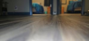 Un suelo de madera que conduce a una habitación con una cama y una mesita de noche.