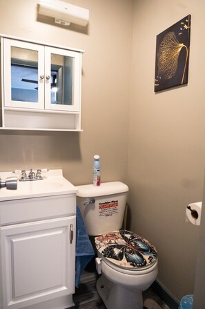 Une salle de bain équipée de toilettes, d’un lavabo, d’un meuble de rangement et d’un climatiseur fixé au mur.