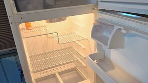 Un refrigerador abierto con estantes, cajones, dispensador de agua y compartimento congelador.
