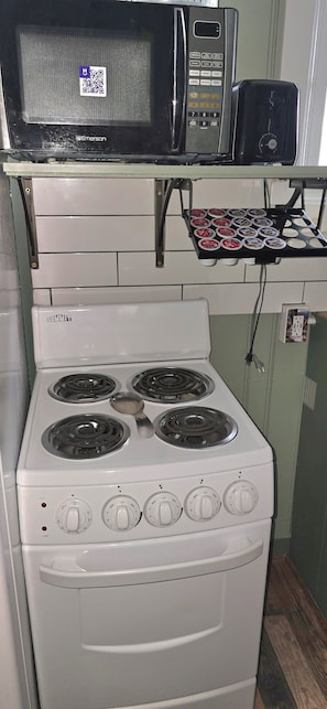 A kitchen with a white stove, a microwave, and a toaster on a shelf.